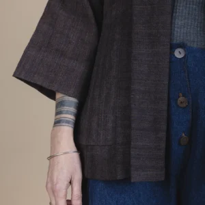 zoom in details of woman wearing brown jacket with tattoos on her wrist