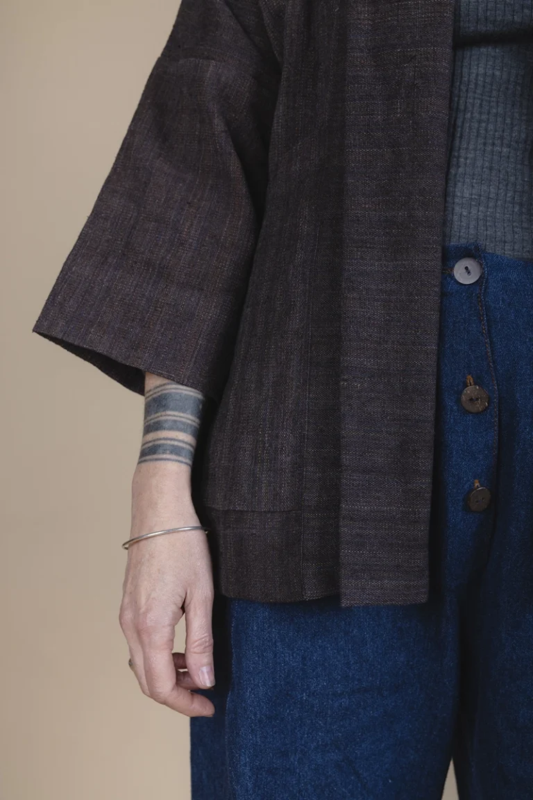zoom in details of woman wearing brown jacket with tattoos on her wrist