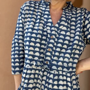 Woman wearing Roamni indigo Dabu block print button front dress with drawstring waist and side pockets.