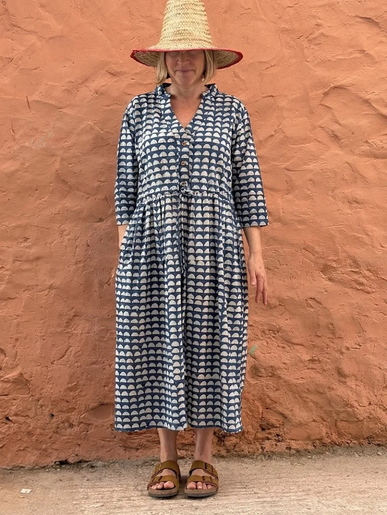 Woman wearing Roamni indigo Dabu block print button front dress with drawstring waist and side pockets.
