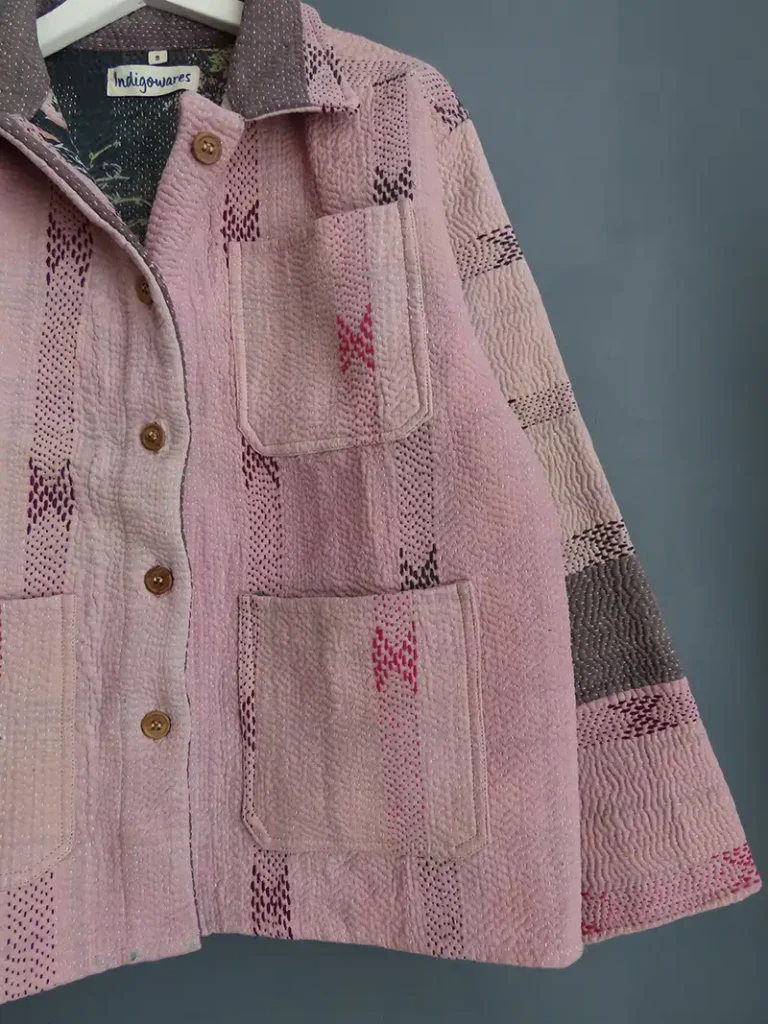 Close-up of pale pink hand-stitched kantha embroidery on a vintage cotton chore jacket.