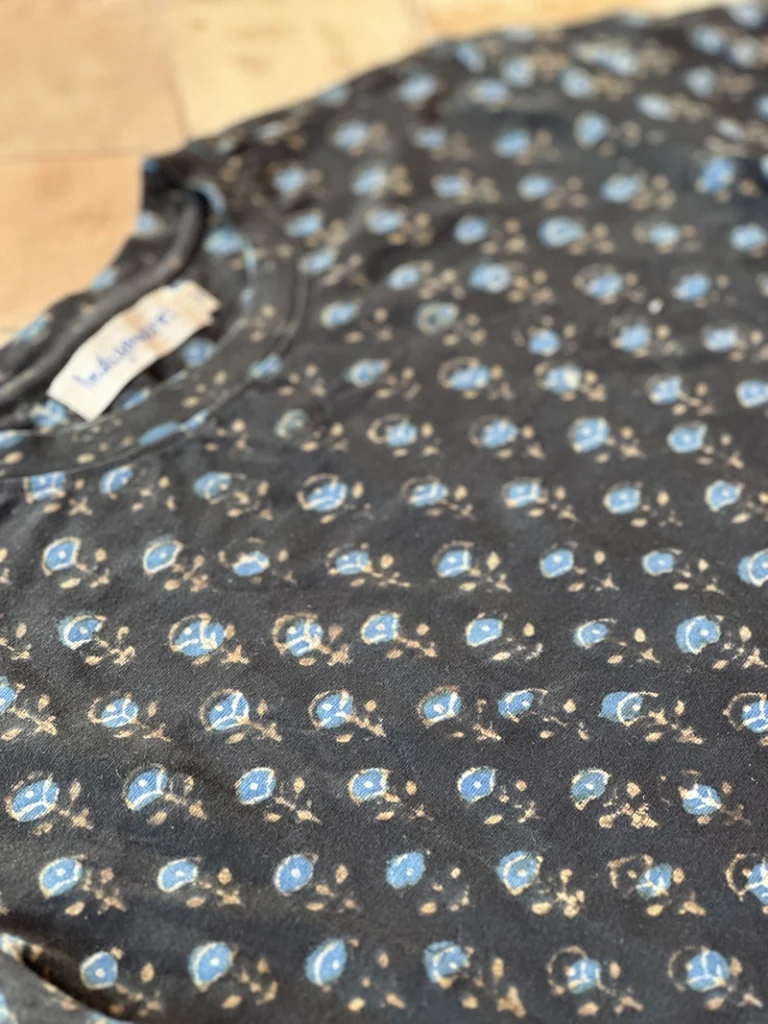 Close up of indigo blue T-shirt featuring a white ditsy floral Dabu hand-block print.