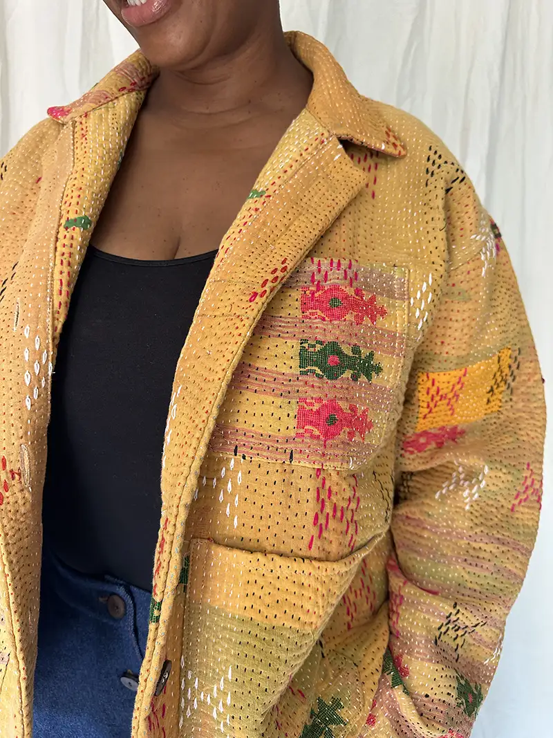 zoom in detail woman wearing a golden yellow kantha chore jacket