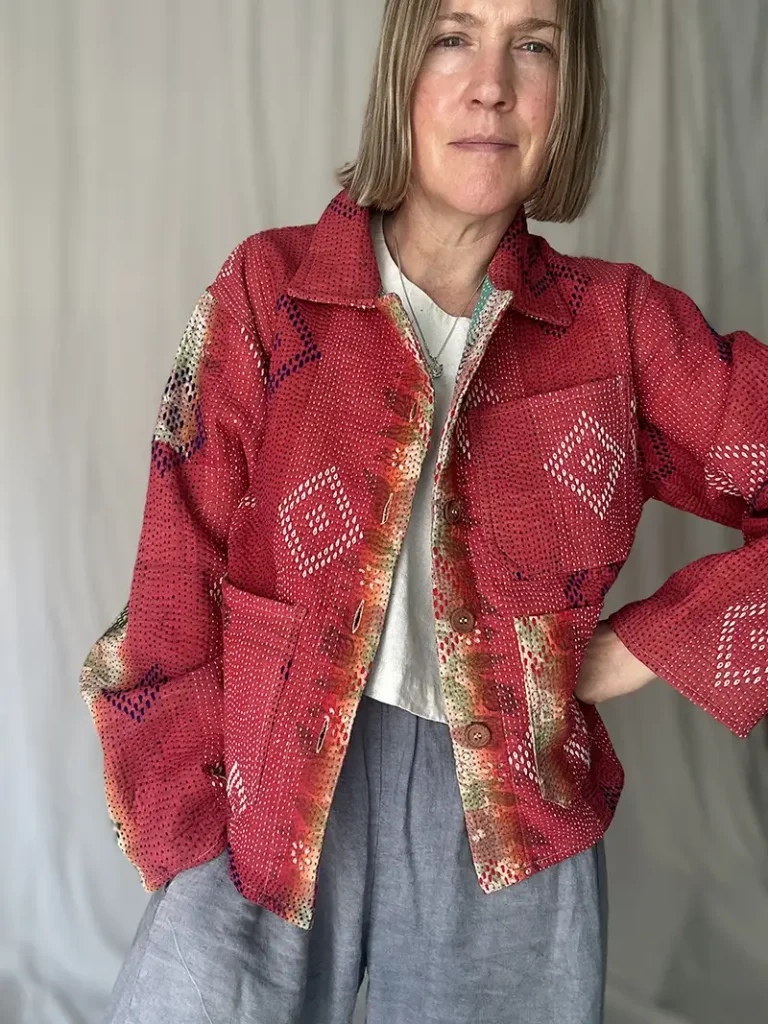 zoom in woman wearing bright red kantha chore jacket