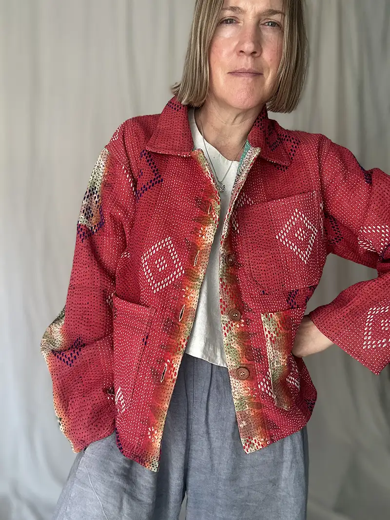 zoom in woman wearing bright red kantha chore jacket