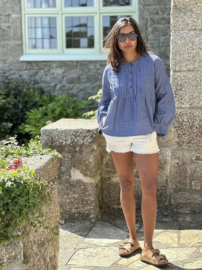 woman wearing artisan pintuck blouse with white shorts