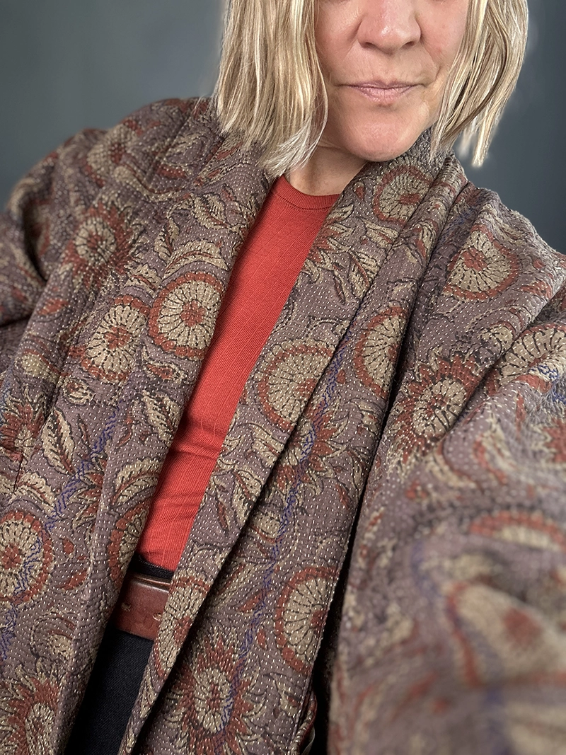zoom in woman wearing a vintage indian kantha jacket in dark tones