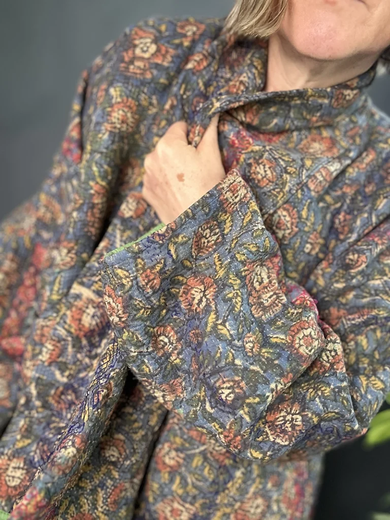 zoom in of woman wearing a dark floral kantha jacket