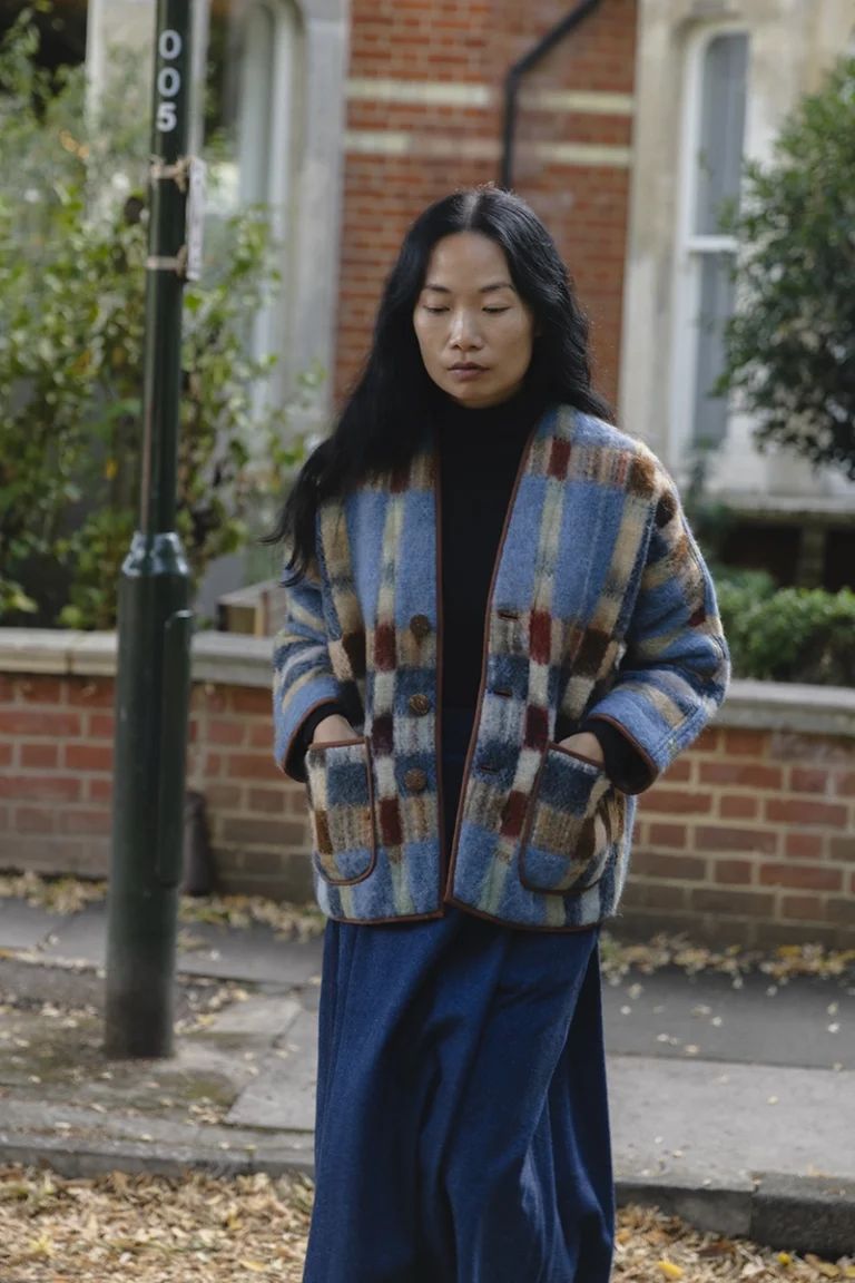 woman with long black hair wearing blue check blanket jacket