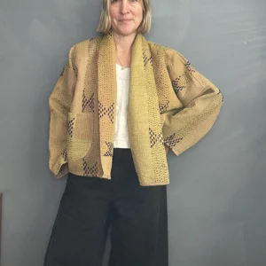 woman wearing a sand coloured short kantha jacket with black jeans