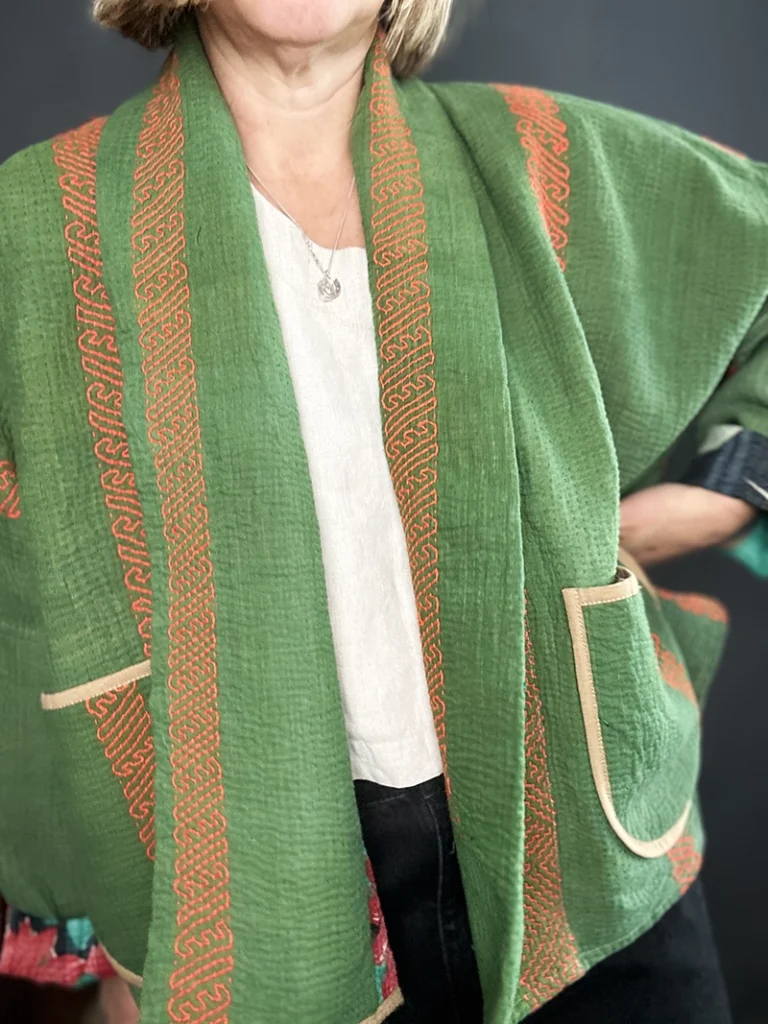 zoom in woman wearing a reversible green quilted kantha jacket