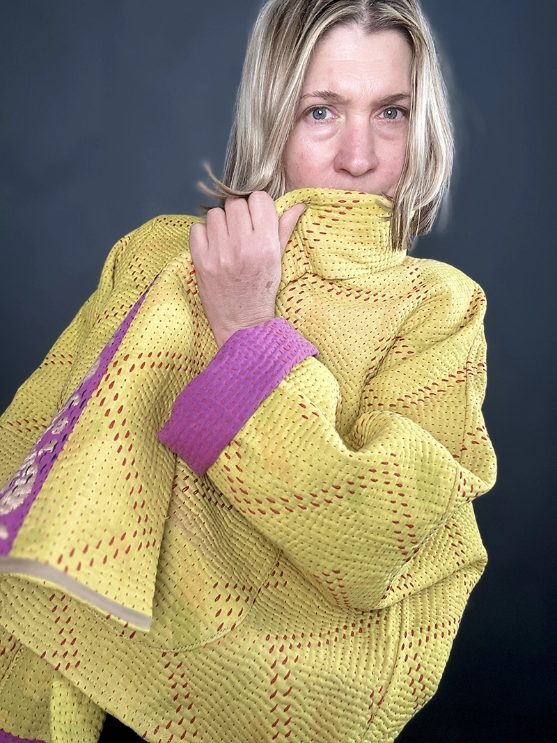 zoom in woman wearing a yellow and pink reversible kantha quilted jacket